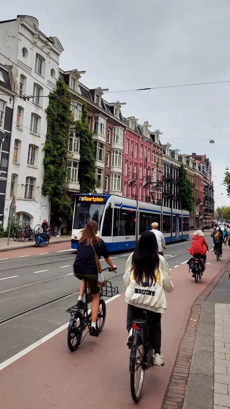 Cyclists riding in a red bike lane next to a tram in Amsterdam