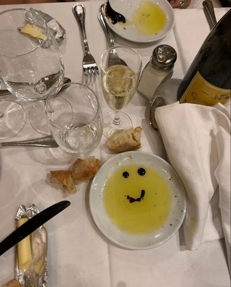 A restaurant table in Italy with bread, olive oil and glasses, the kind of meal where a coperto shows up on the bill