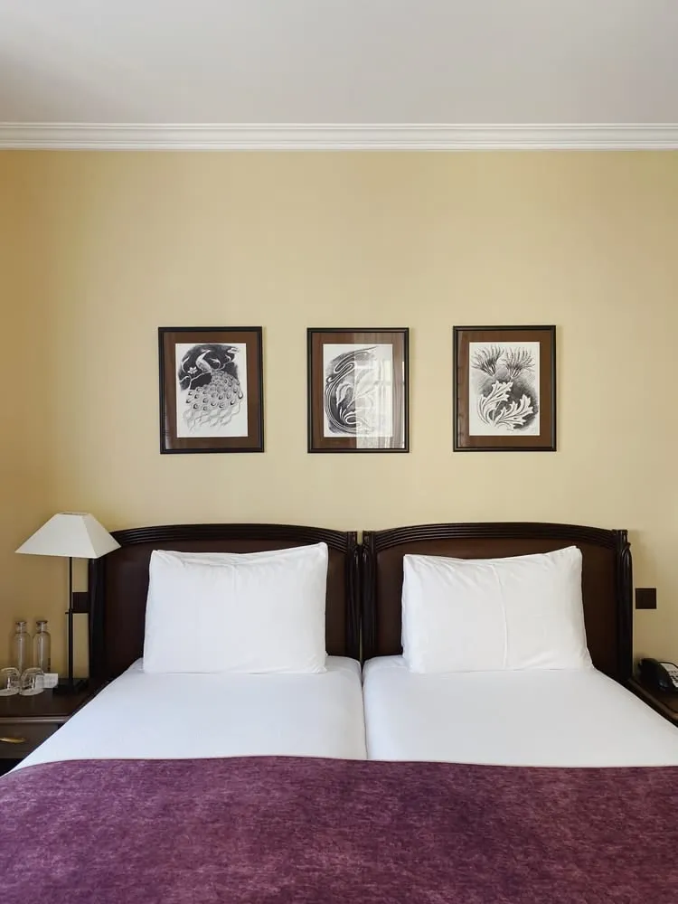 A European hotel room with two single beds pushed together under one headboard